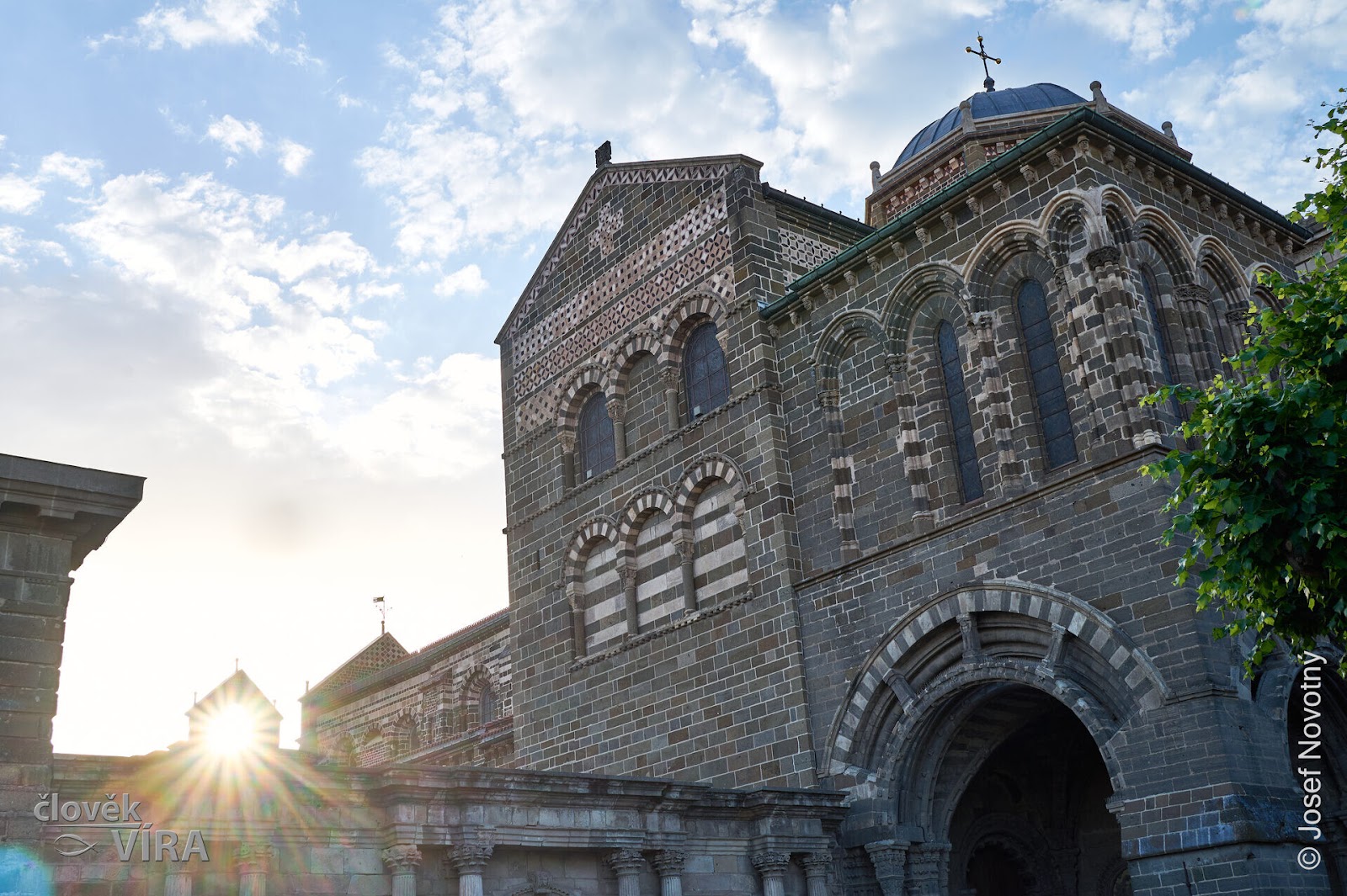 Stone church facade with the sun breaking over the roof