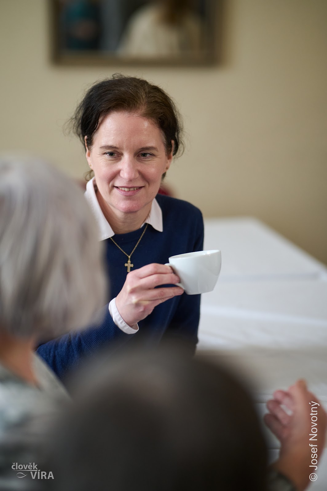 Woman in a dark jacket holding a coffee cup, smiling
