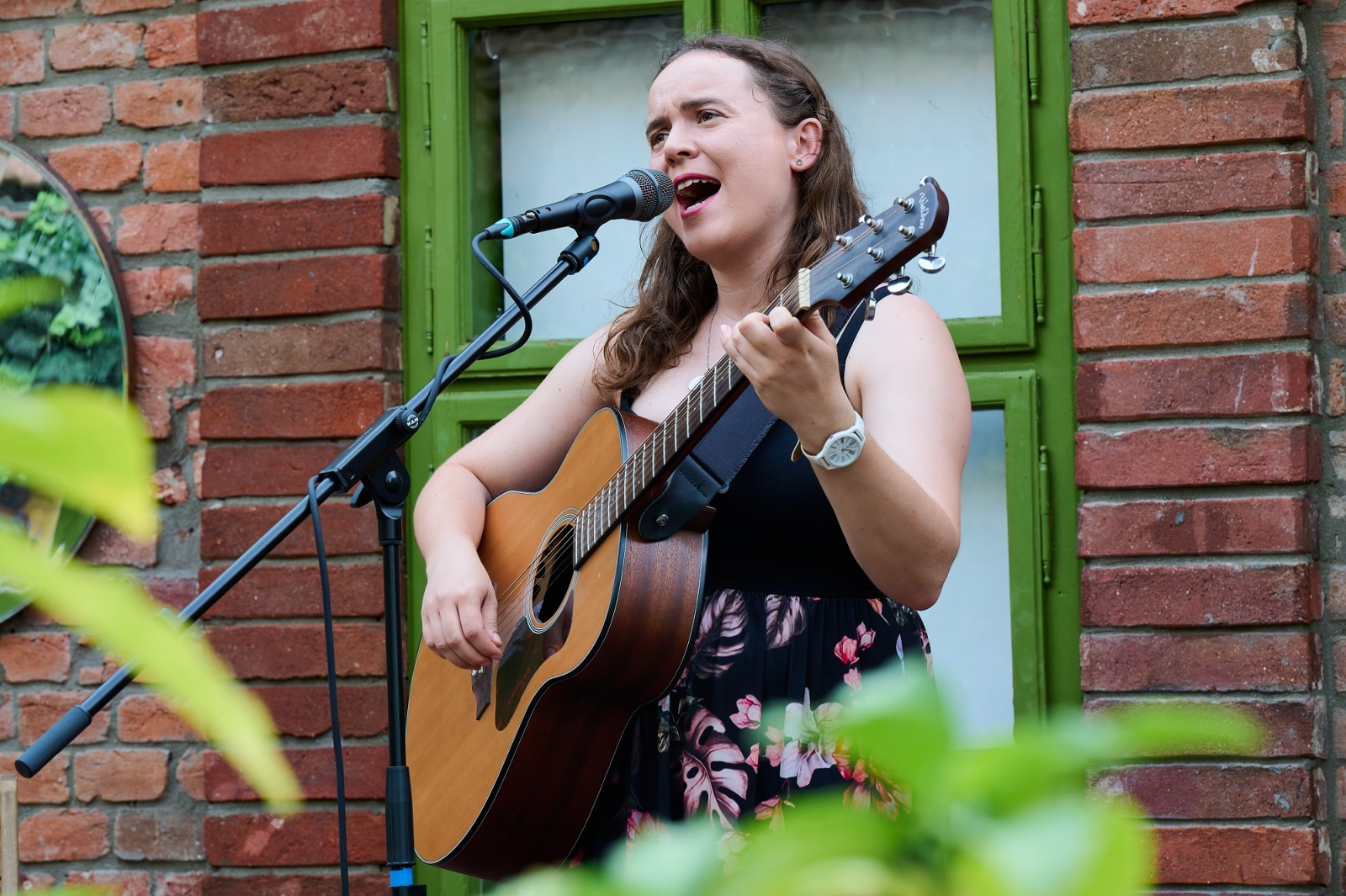 Singer with an acoustic guitar performing outdoors by a green door