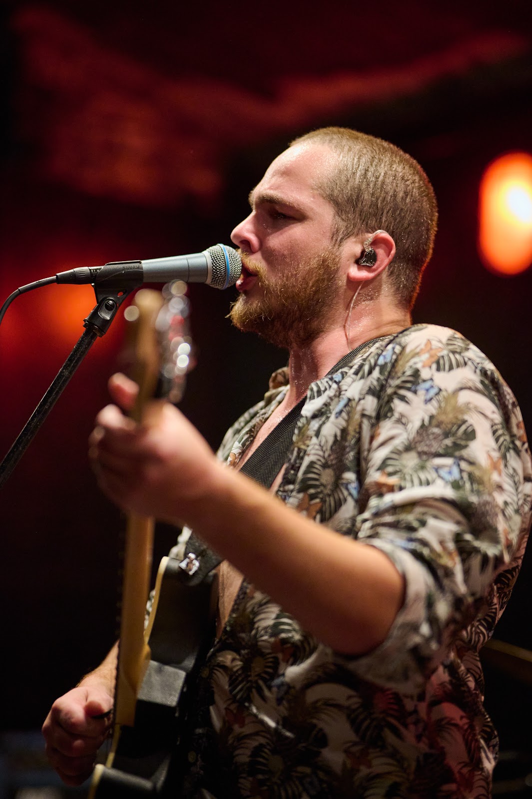 Singer in a camouflage shirt leaning into the microphone