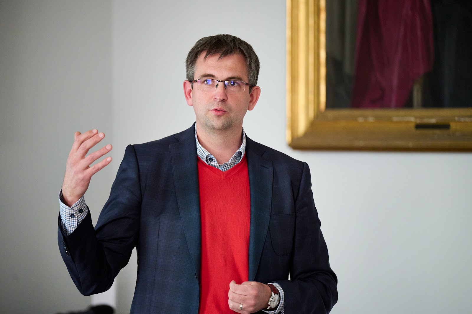 Speaker in a red sweater gesturing mid-sentence
