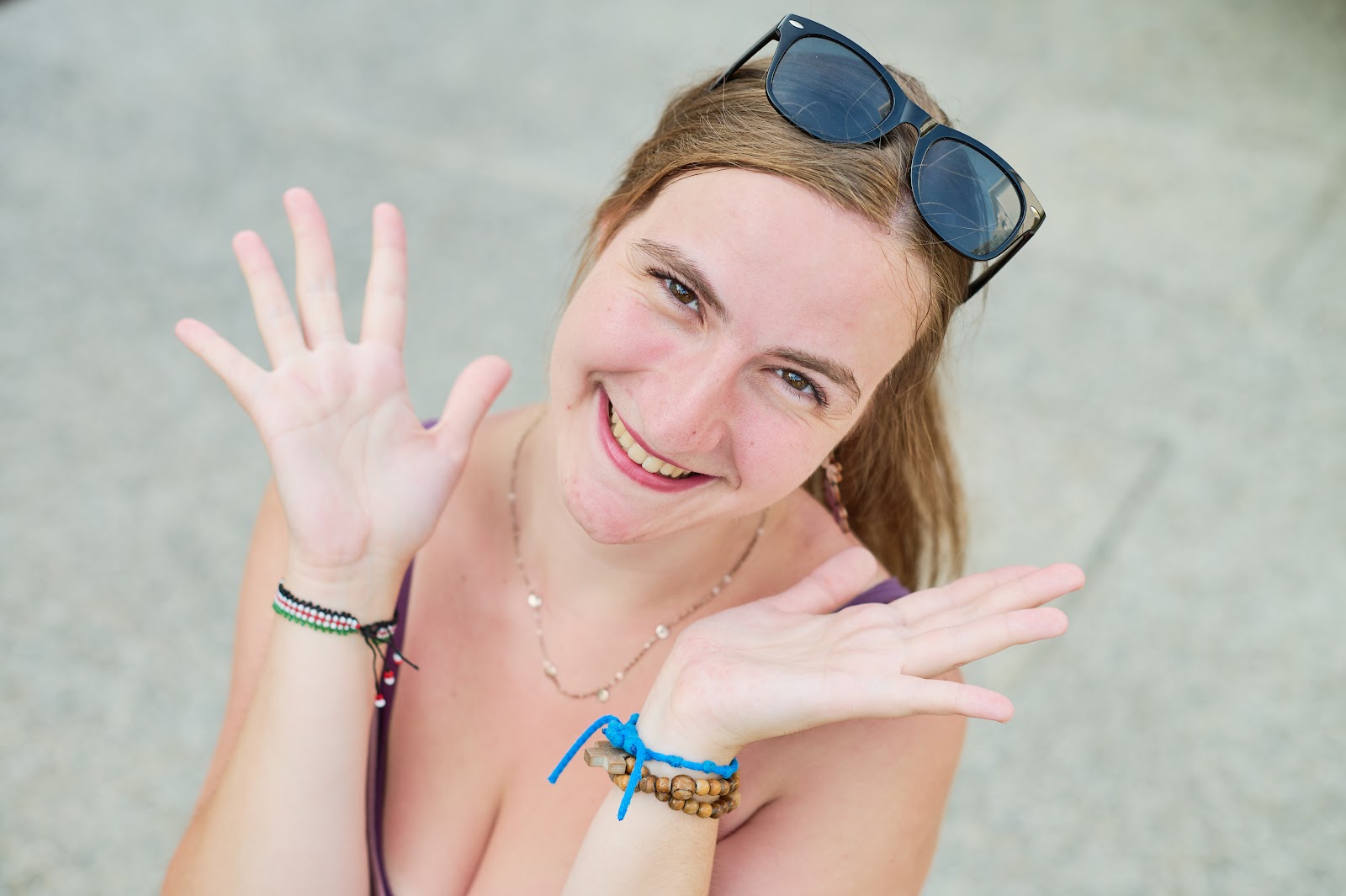 Laughing woman with sunglasses in her hair, hands raised