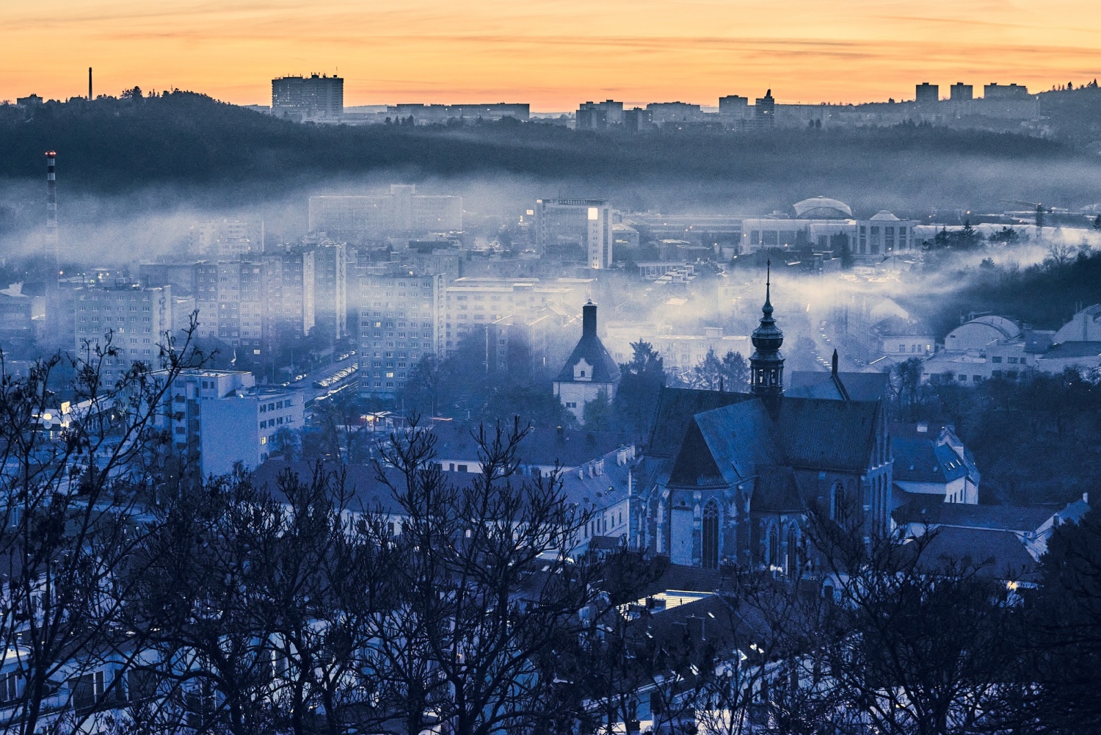 Brno rooftops and church towers in evening fog